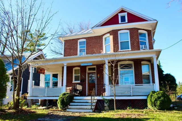A straight-on view of a three-story brick house with a porch