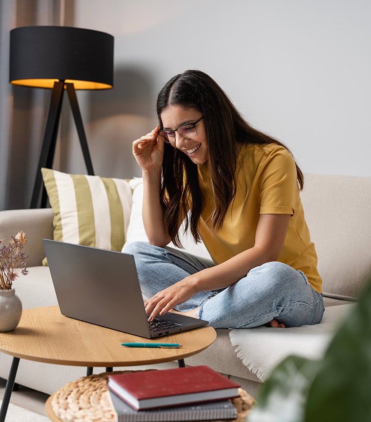 A female college student using a laptop while sitting on a couch